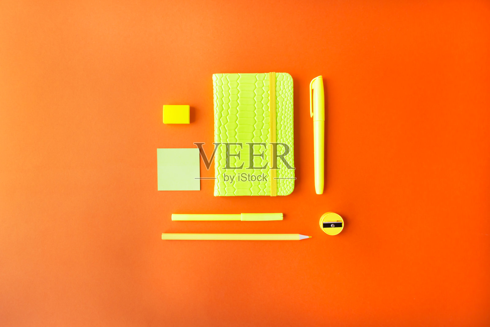 诺尔学校或办公用品。记事本，记号笔和铅笔在橙色的背景霓虹色。照片摄影图片