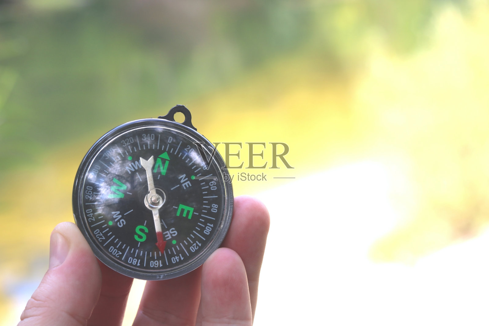 夏日沙滩背景下，经典的航海罗盘在手照片摄影图片