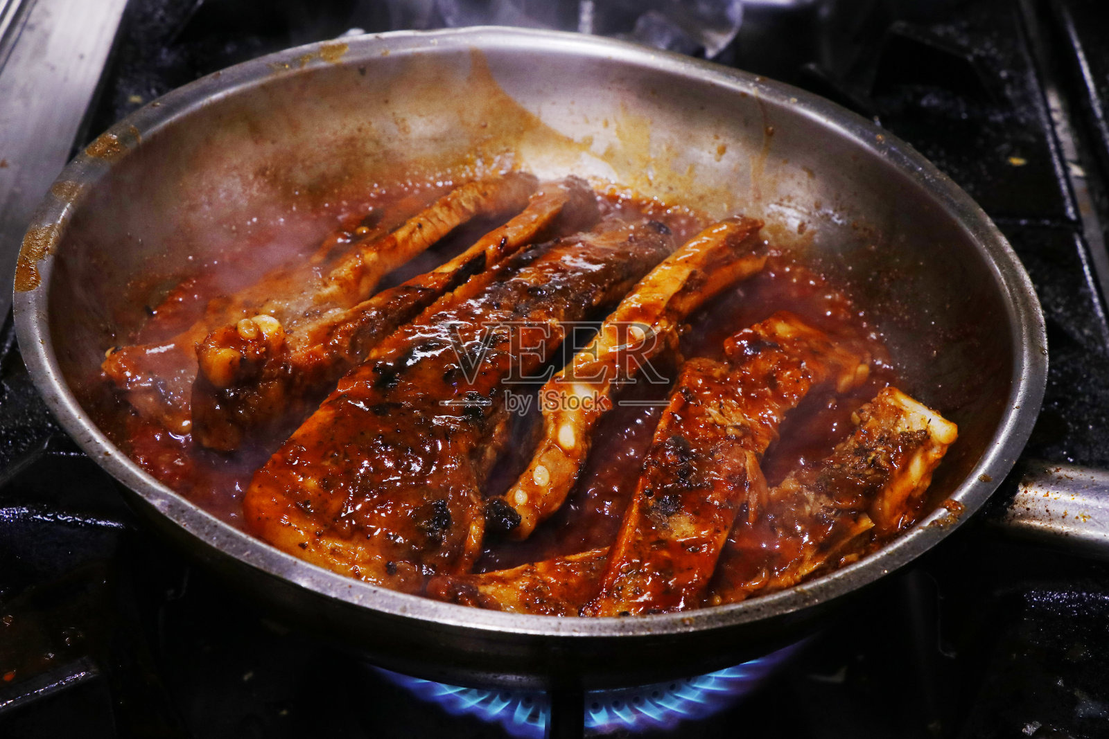 锅中淋着辣酱的黏性烤猪肋排照片摄影图片