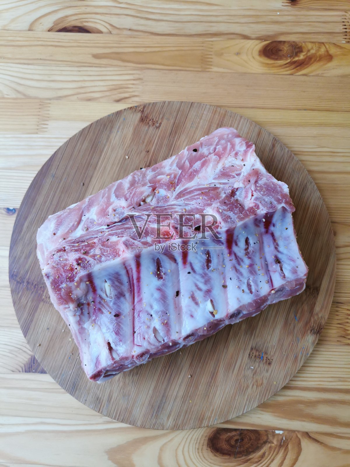 排骨上的猪肉，填满大蒜，准备烘烤，躺在一个圆木板上的木制背景照片摄影图片