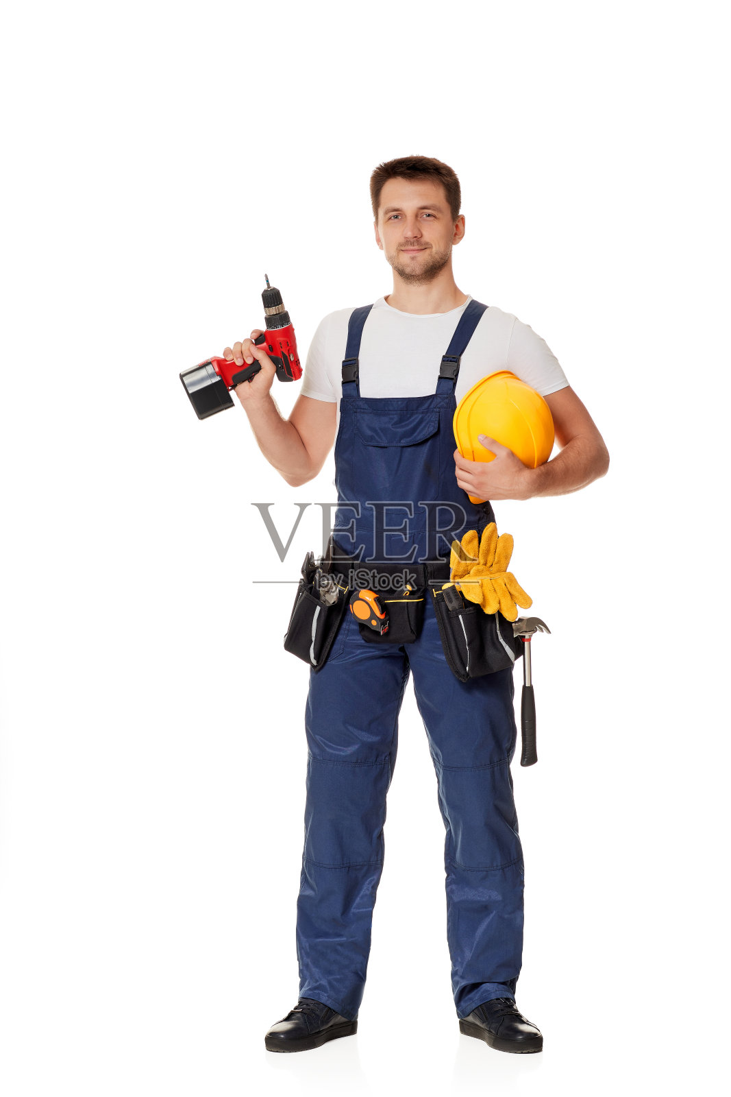 年轻的白人修理工戴着黄色安全帽，手持无绳螺丝刀照片摄影图片