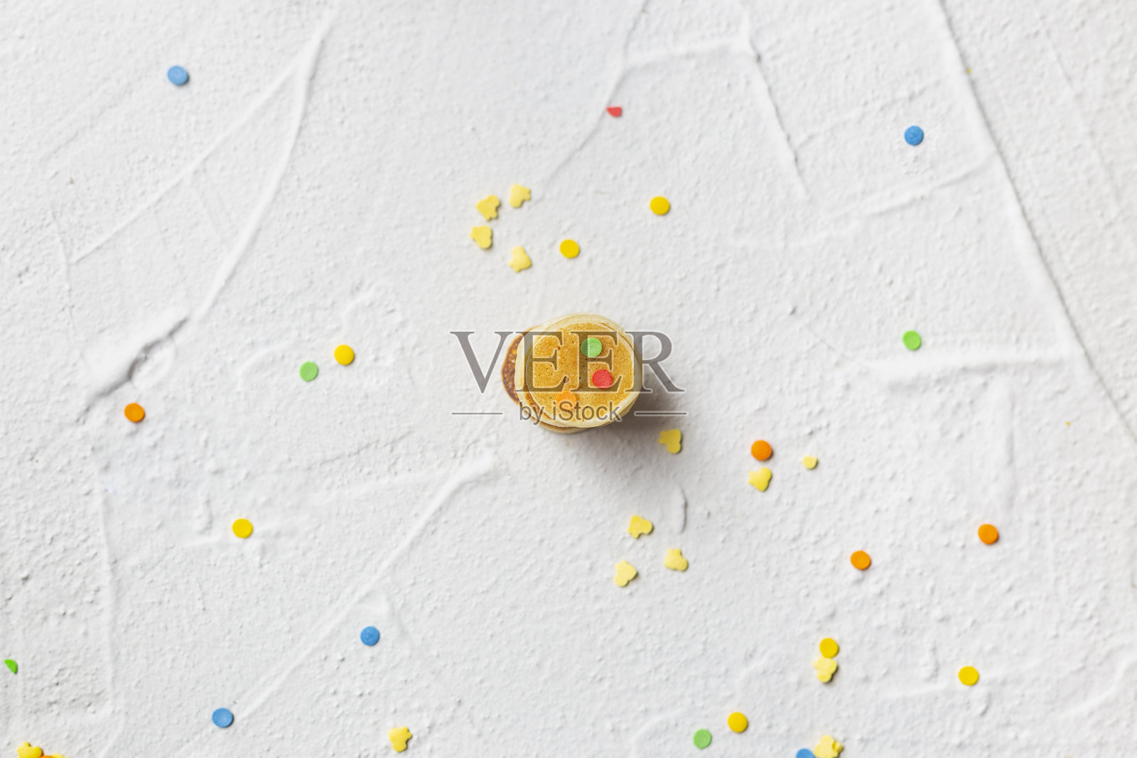 灰色纹理背景上的小煎饼和多色糖果。照片摄影图片