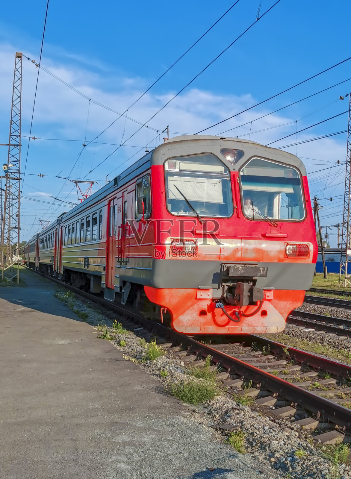 夏天，红色的电动火车在车站附近的轨道上行驶照片摄影图片