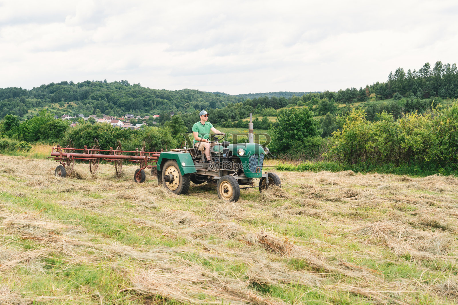 一个人操纵着晒草机给田里的干草通风照片摄影图片