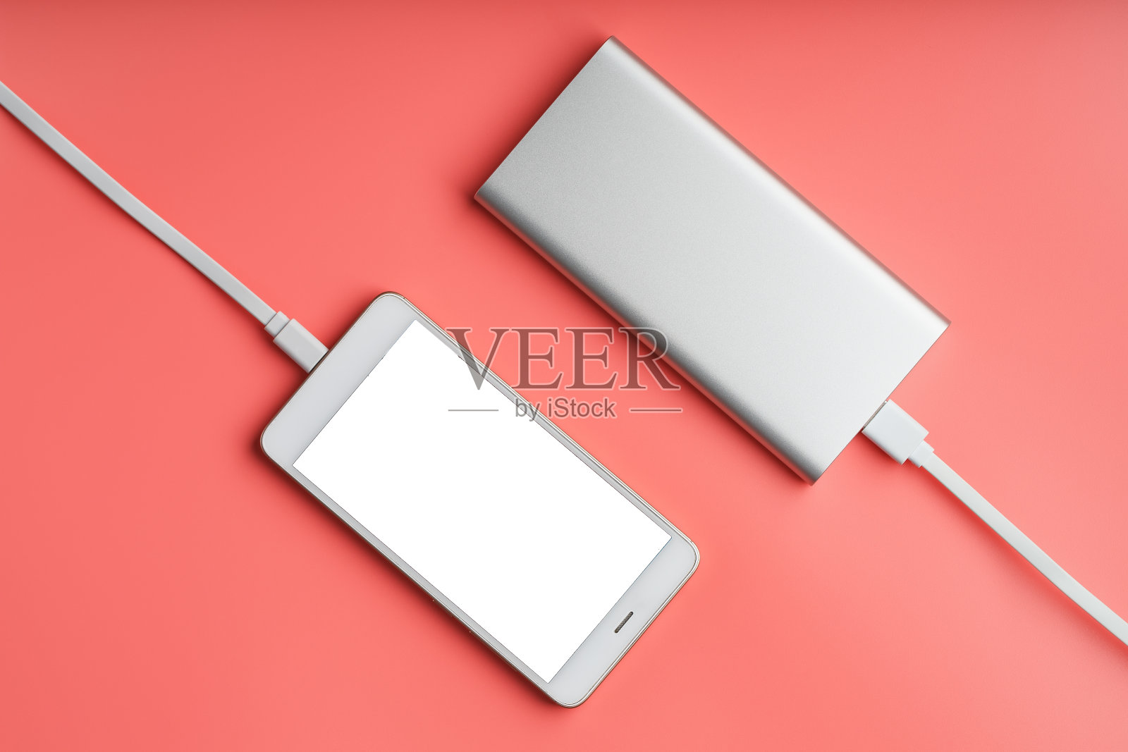 Powerbank以粉色为背景为智能手机充电。通用外接电池的小玩意自由的空间和极简的组成。照片摄影图片