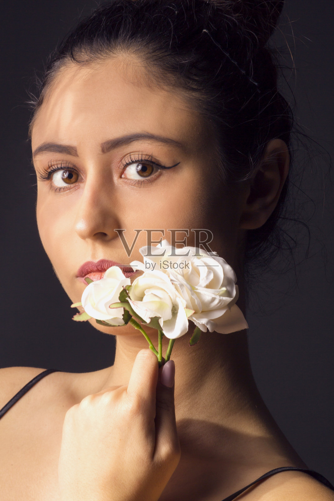 漂亮的年轻女孩拿着五颜六色的花，画室里的画像照片摄影图片