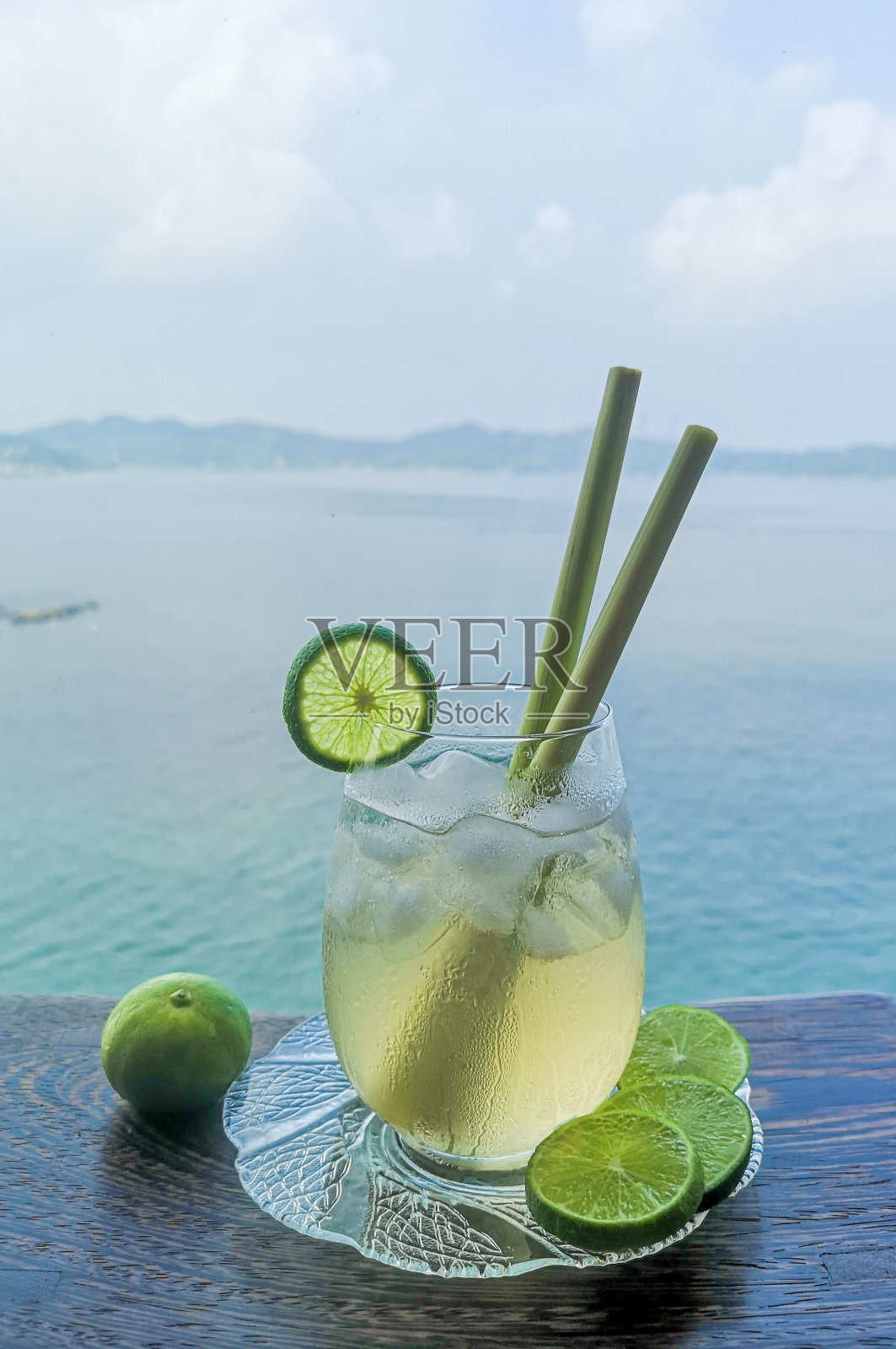 柠檬草蜂蜜冰茶在一个圆形的玻璃杯与海景背景照片摄影图片