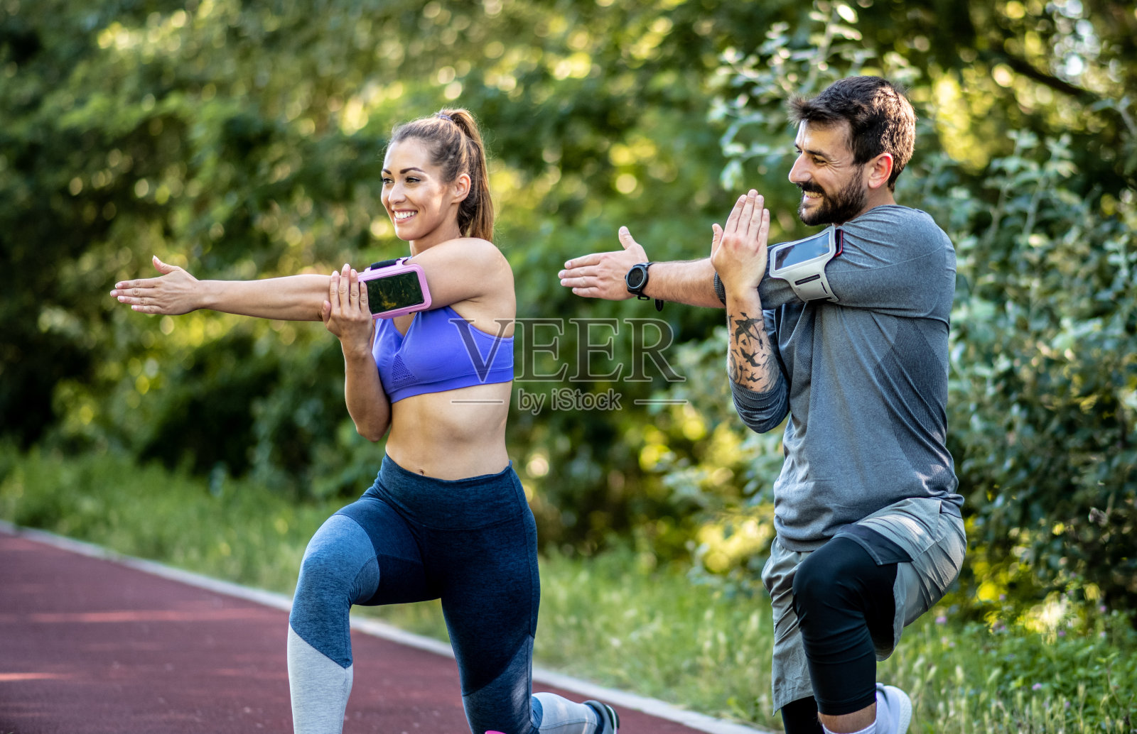 在一个阳光明媚的日子里，一对年轻夫妇在跑步机上做热身运动，他们微笑着照片摄影图片