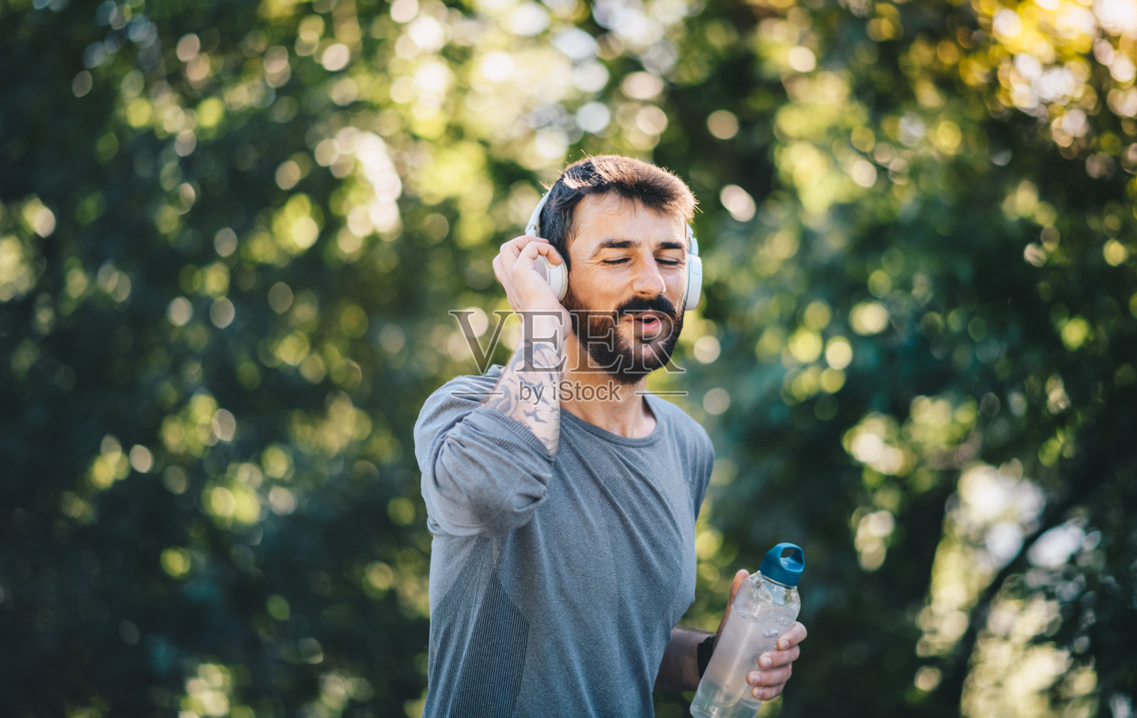 一个年轻人在大自然中慢跑，听着音乐，随身带着一瓶水，慢跑照片摄影图片