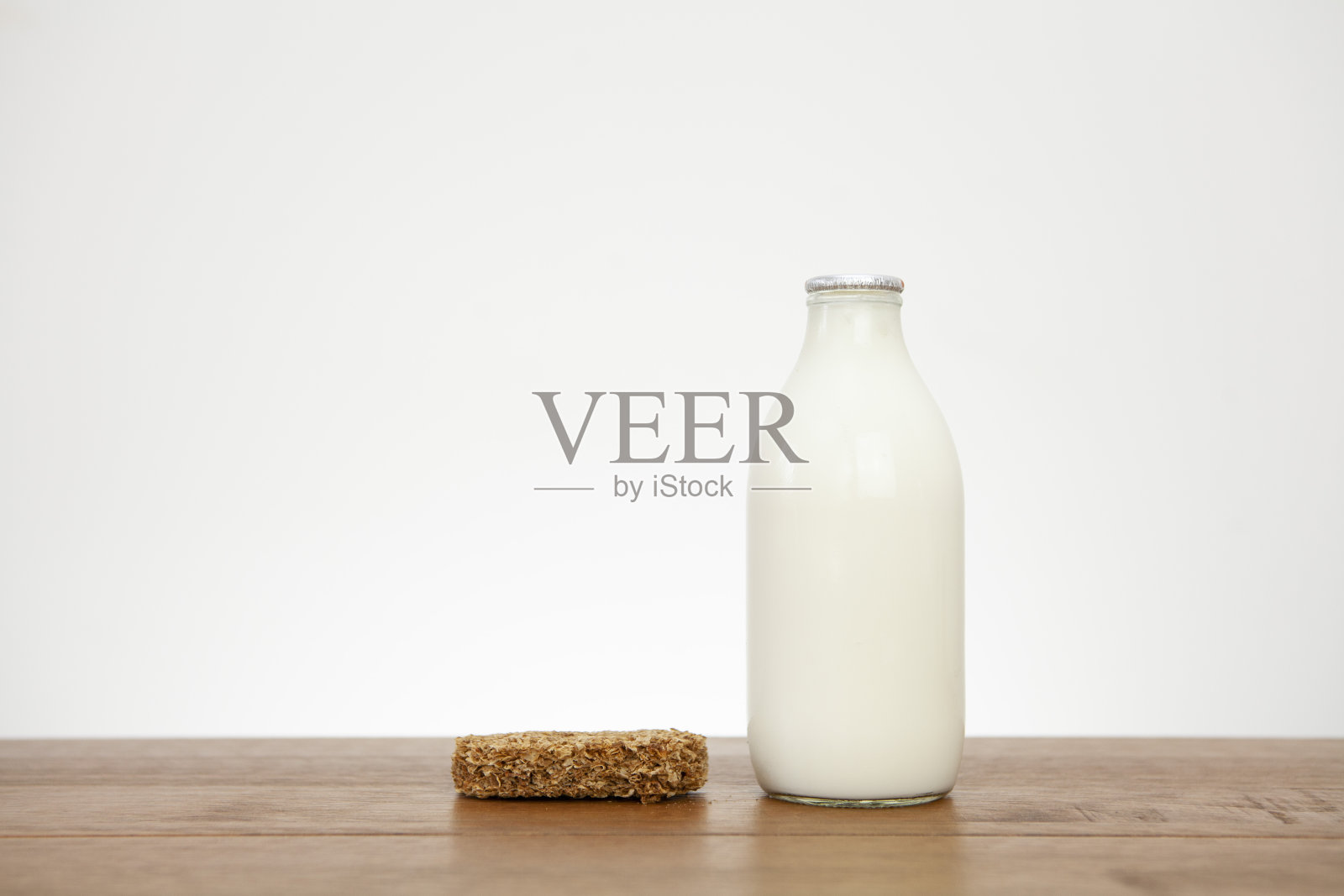 一块维他麦(Weetabix)早餐麦片饼干，旁边是一品脱牛奶，放在一个有复印空间的木质表面上照片摄影图片
