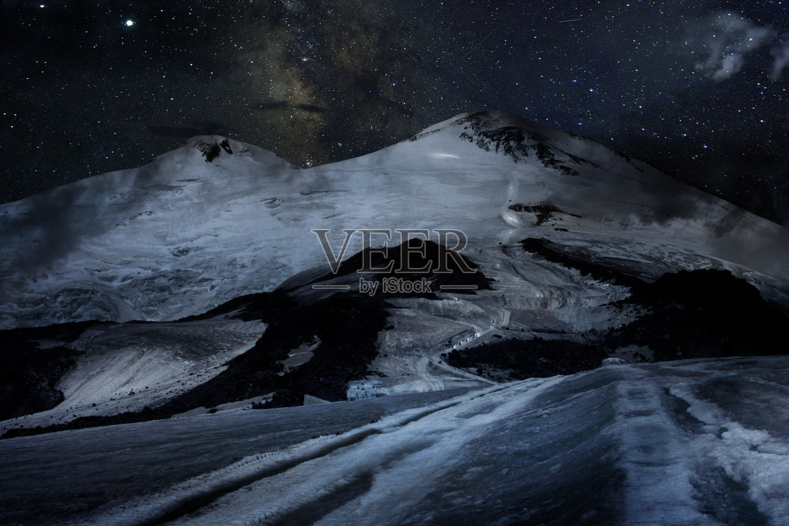 厄尔布鲁士山攀升。白雪皑皑的山峰和夜晚的登山者。照片摄影图片