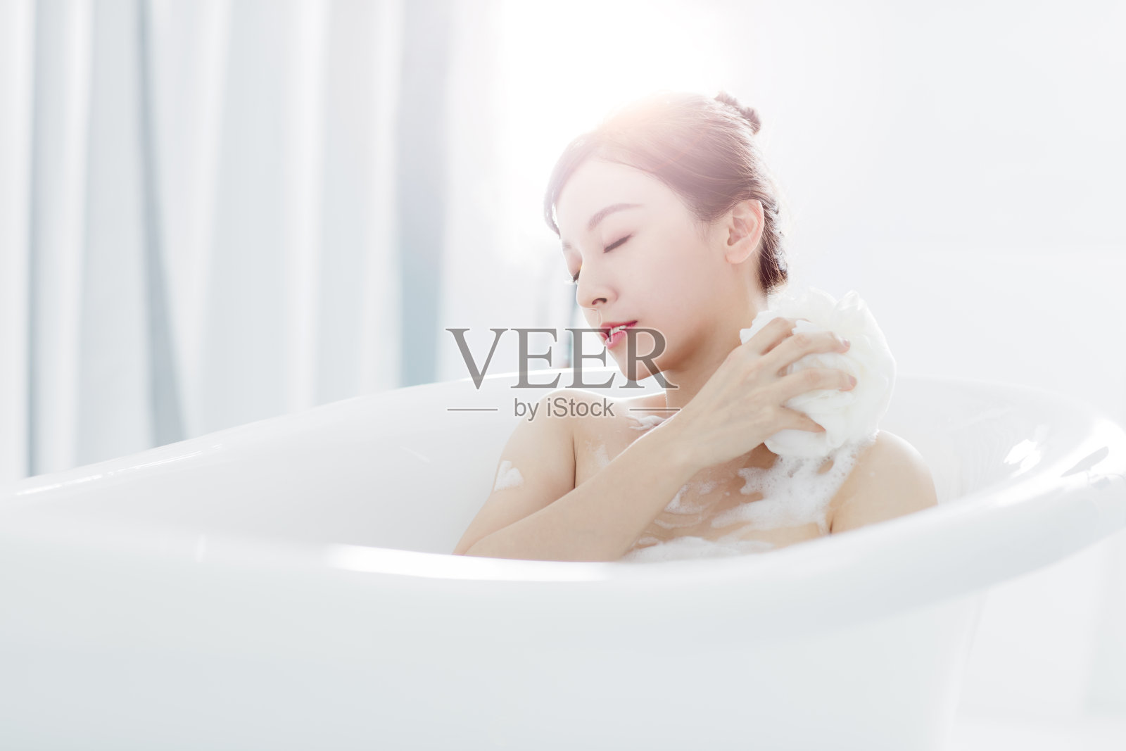 年轻女子在浴缸里洗澡照片摄影图片