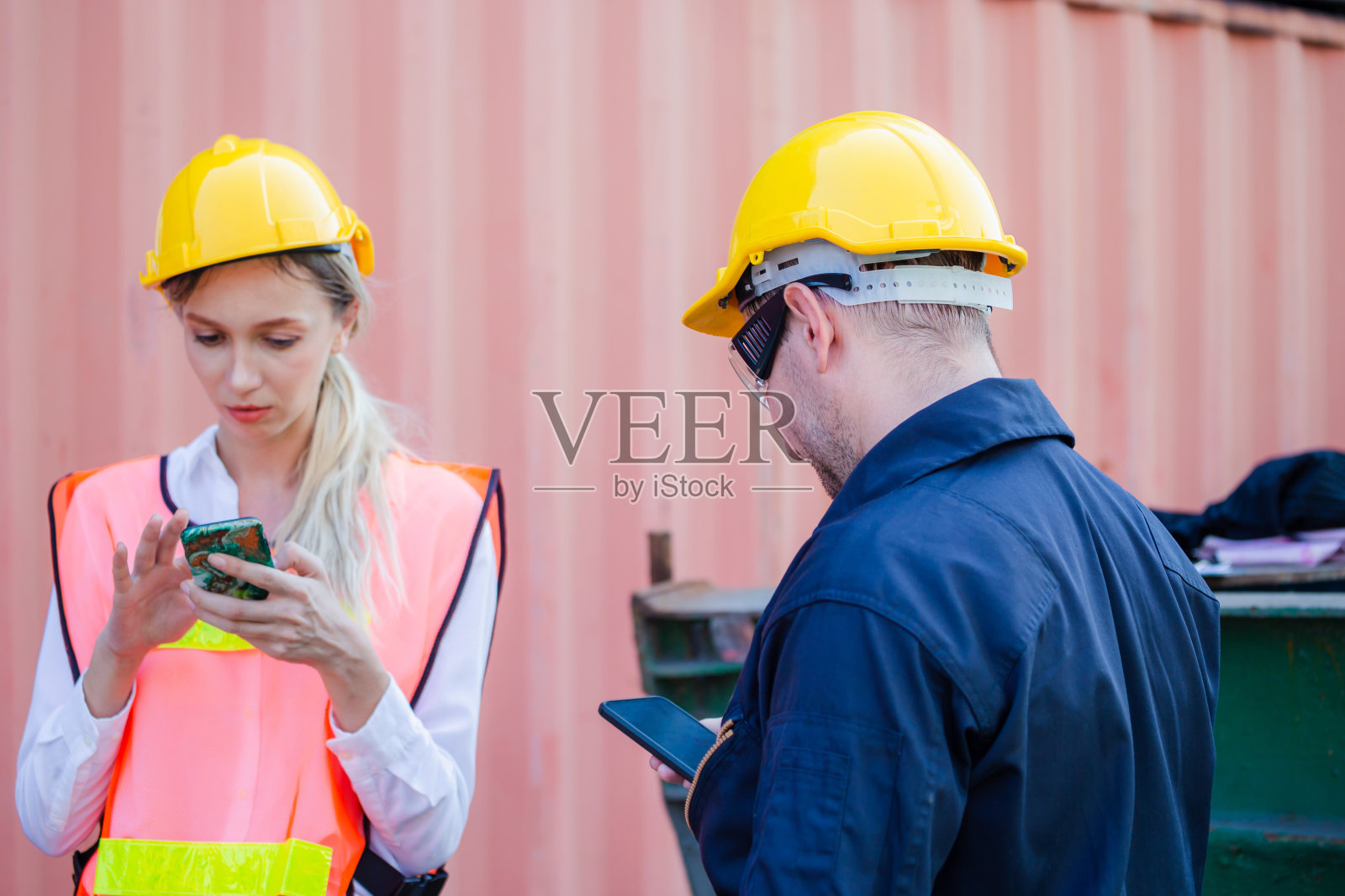 工程师在安全帽中使用手机，产业工人在工业集装箱中使用移动智能手机照片摄影图片