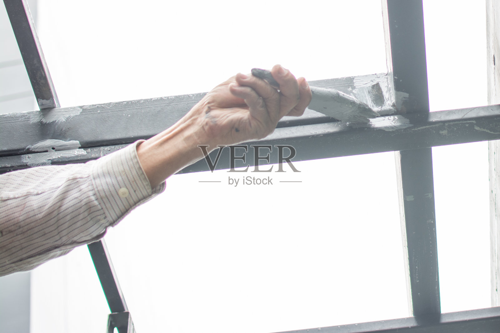 工人粉刷钢屋顶结构，屋顶下顶。照片摄影图片