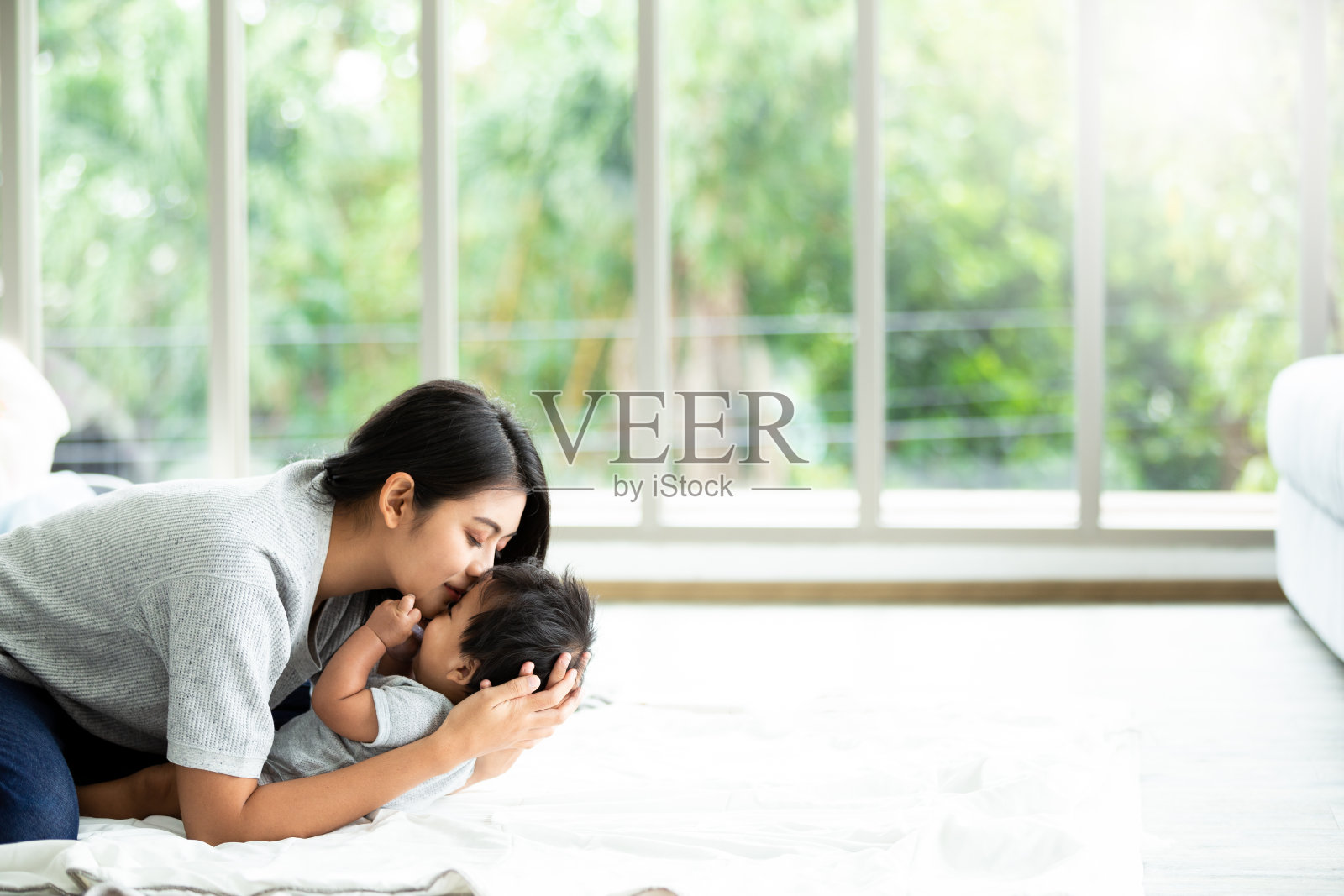 图为一位年轻的母亲在客厅里照顾她刚出生的小男孩。漂亮的妈妈抱着她的孩子。家庭的概念。照片摄影图片