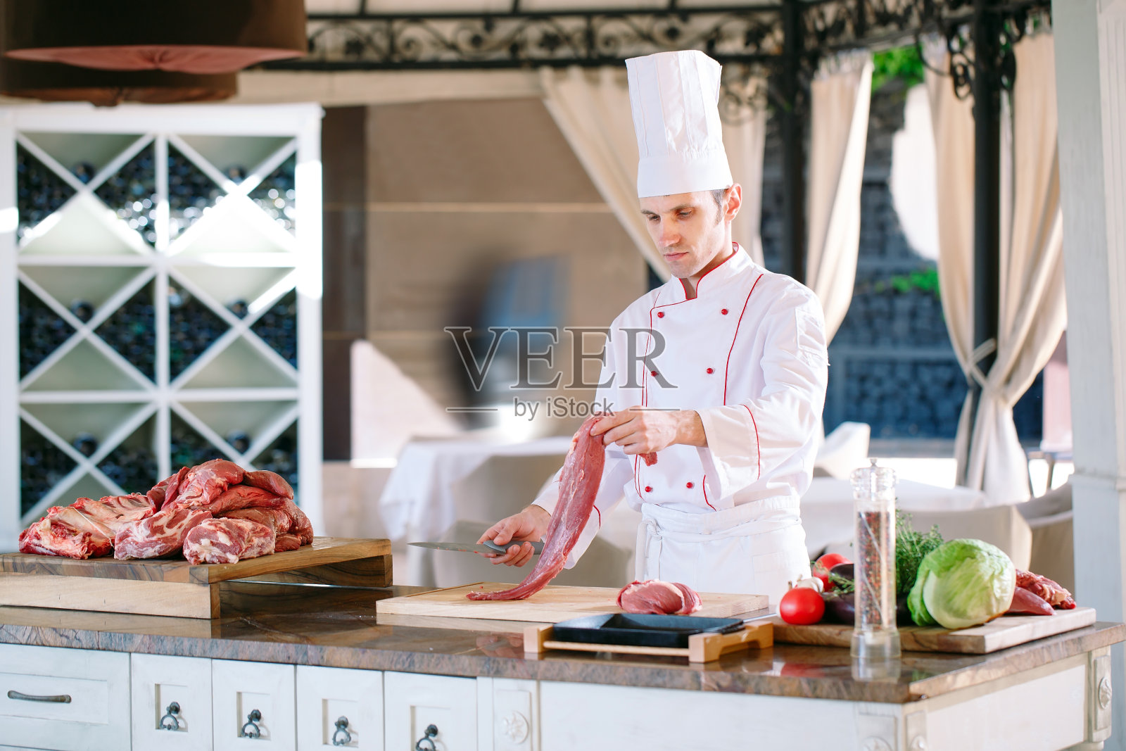 在餐馆里，一个厨师用刀切肉。照片摄影图片
