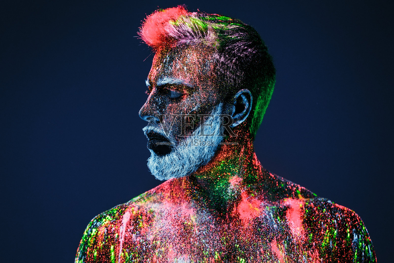 的概念。理发店里的大胡子男人。一个留着时髦胡子的男人正在理发店里理发。这个人用紫外线粉做装饰。照片摄影图片