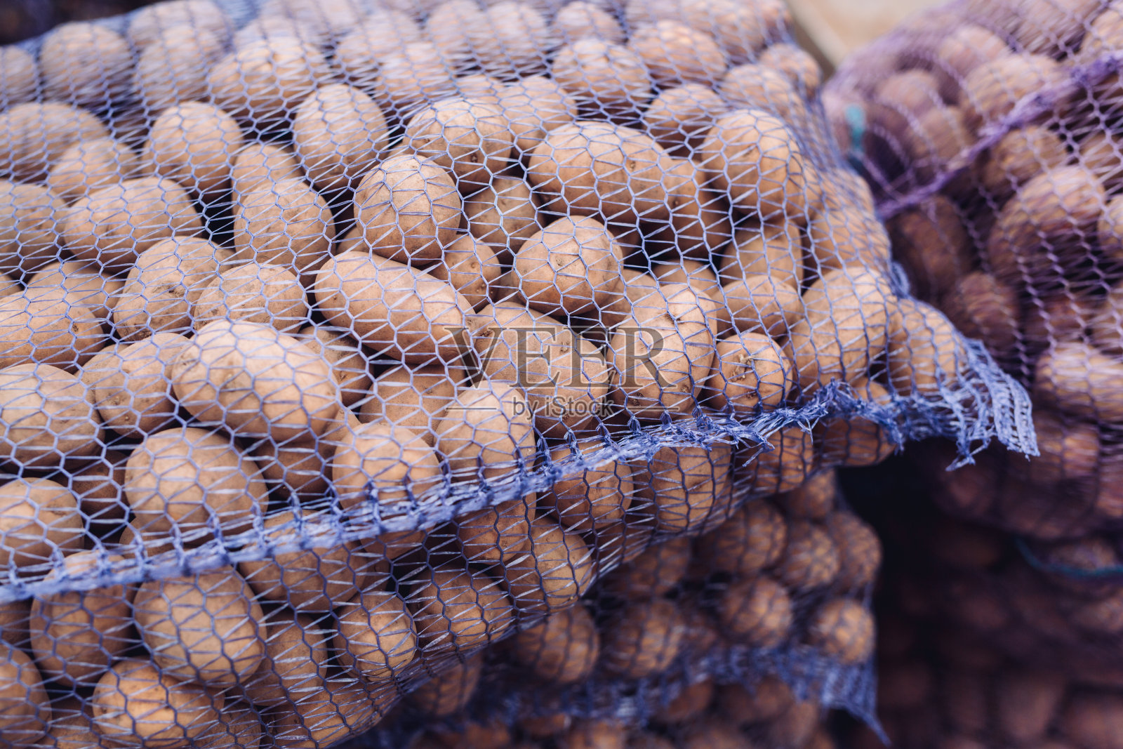 一袋生的脏土豆。网格中的新鲜土豆特写照片摄影图片