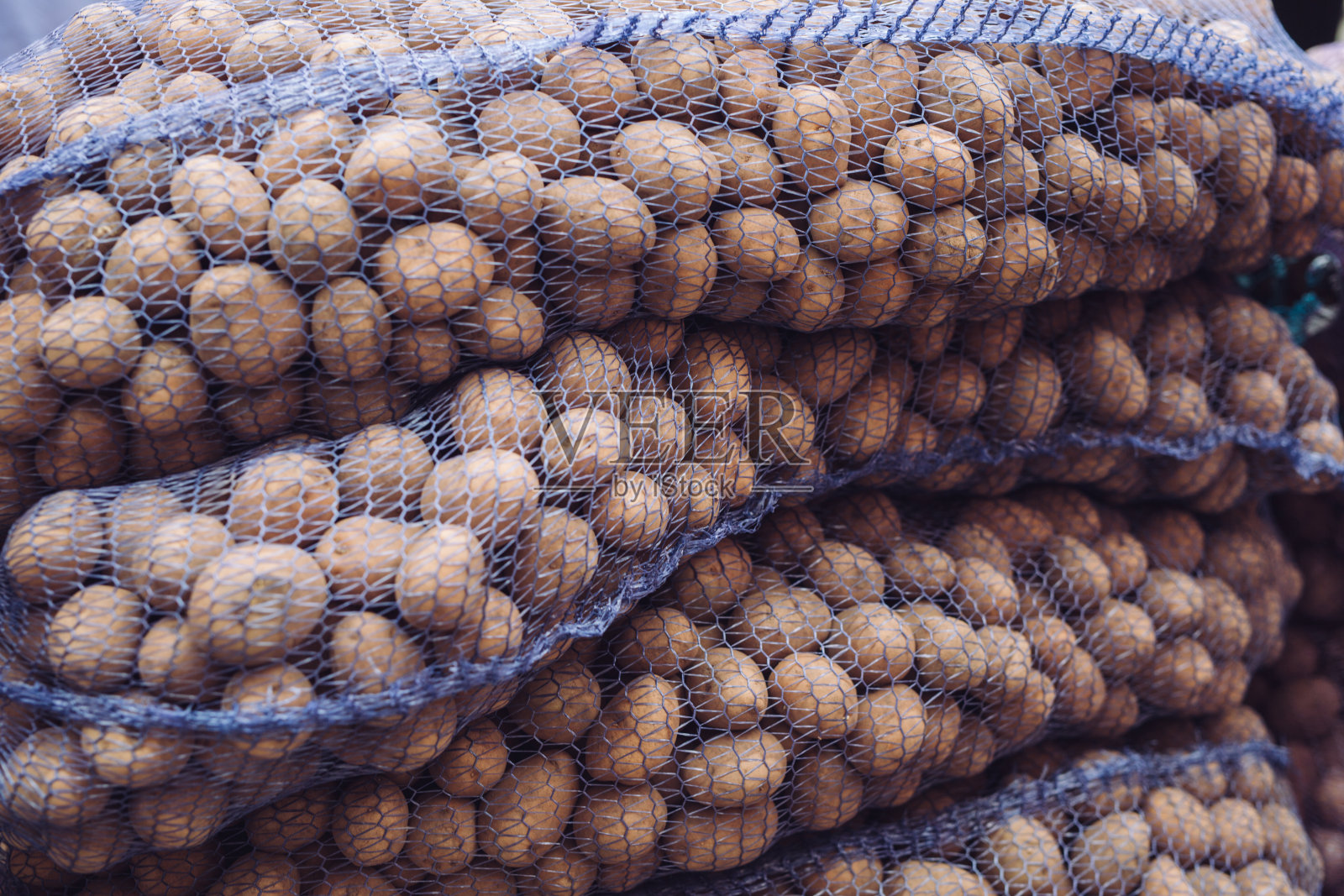 一袋又脏又生的土豆。网格里的新鲜土豆特写。照片摄影图片