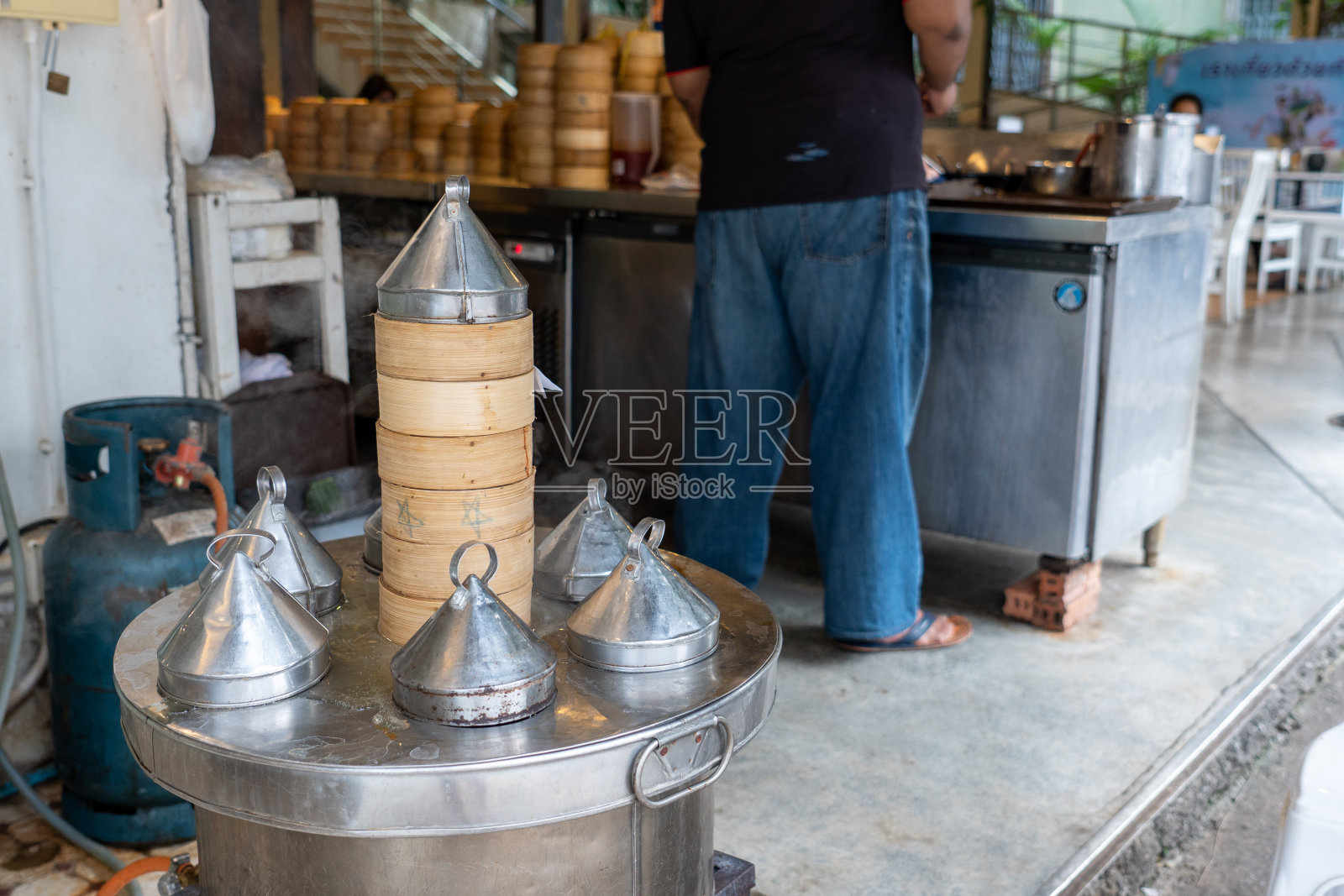 不锈钢蒸笼里的竹篮。照片摄影图片