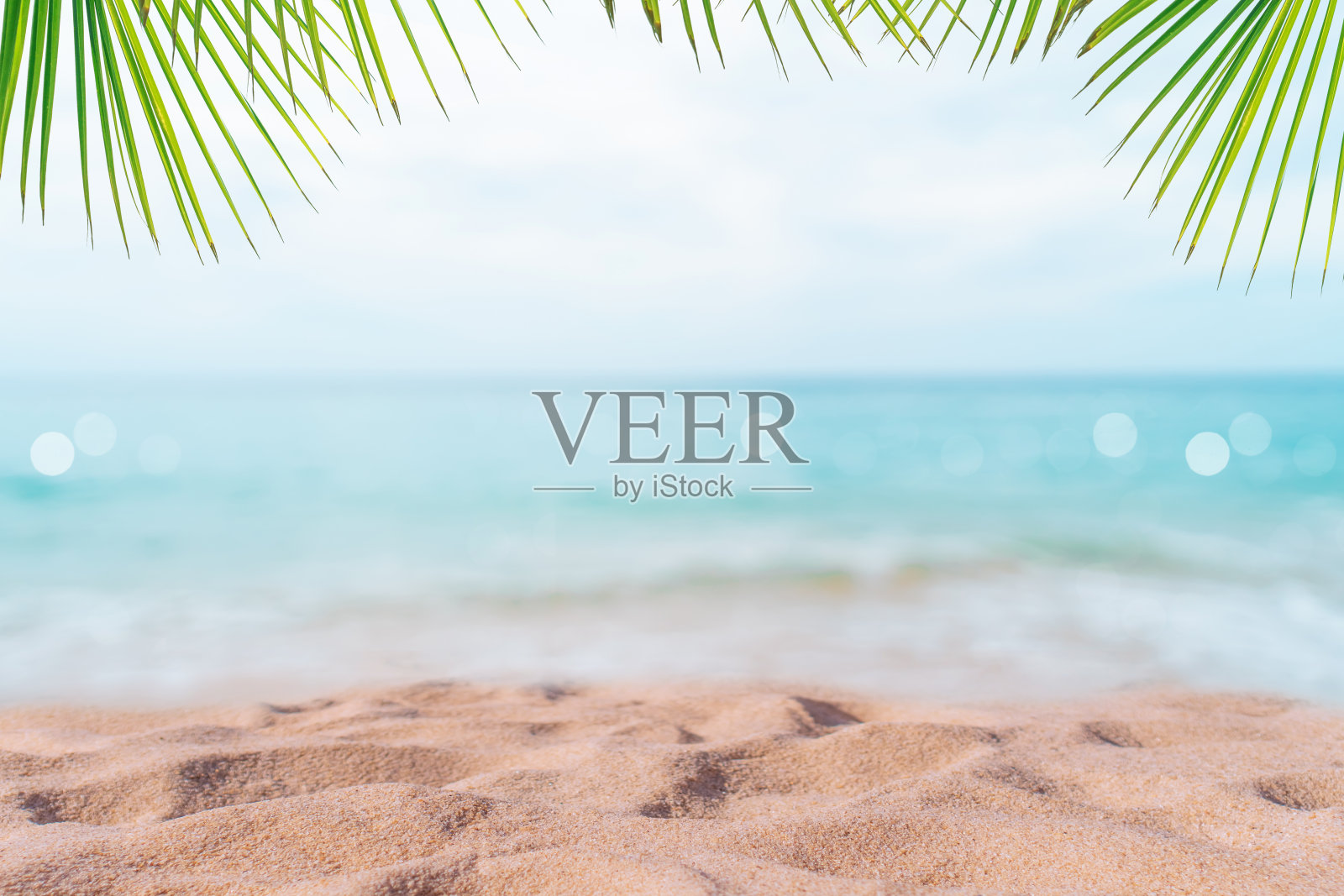 热带自然干净的海滩和白色的沙滩在夏天与棕榈树的叶子，阳光浅蓝色的天空和散景抽象的背景。照片摄影图片