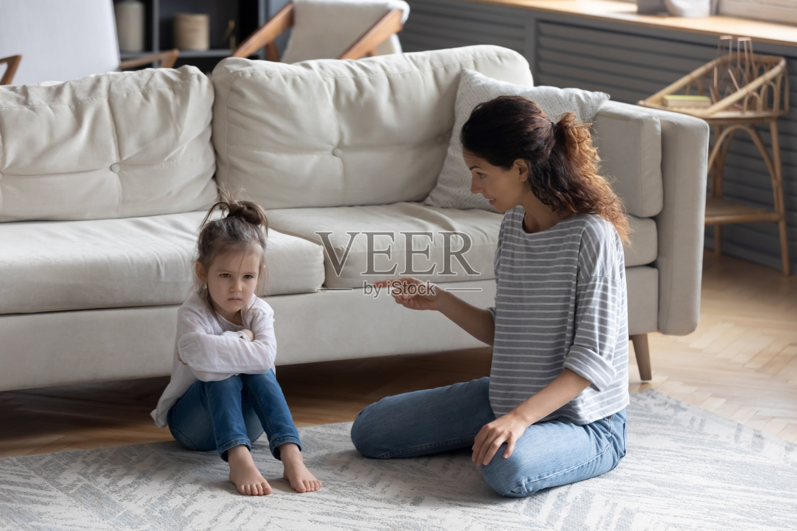 年轻的母亲在训斥压力小的学前班女儿。照片摄影图片