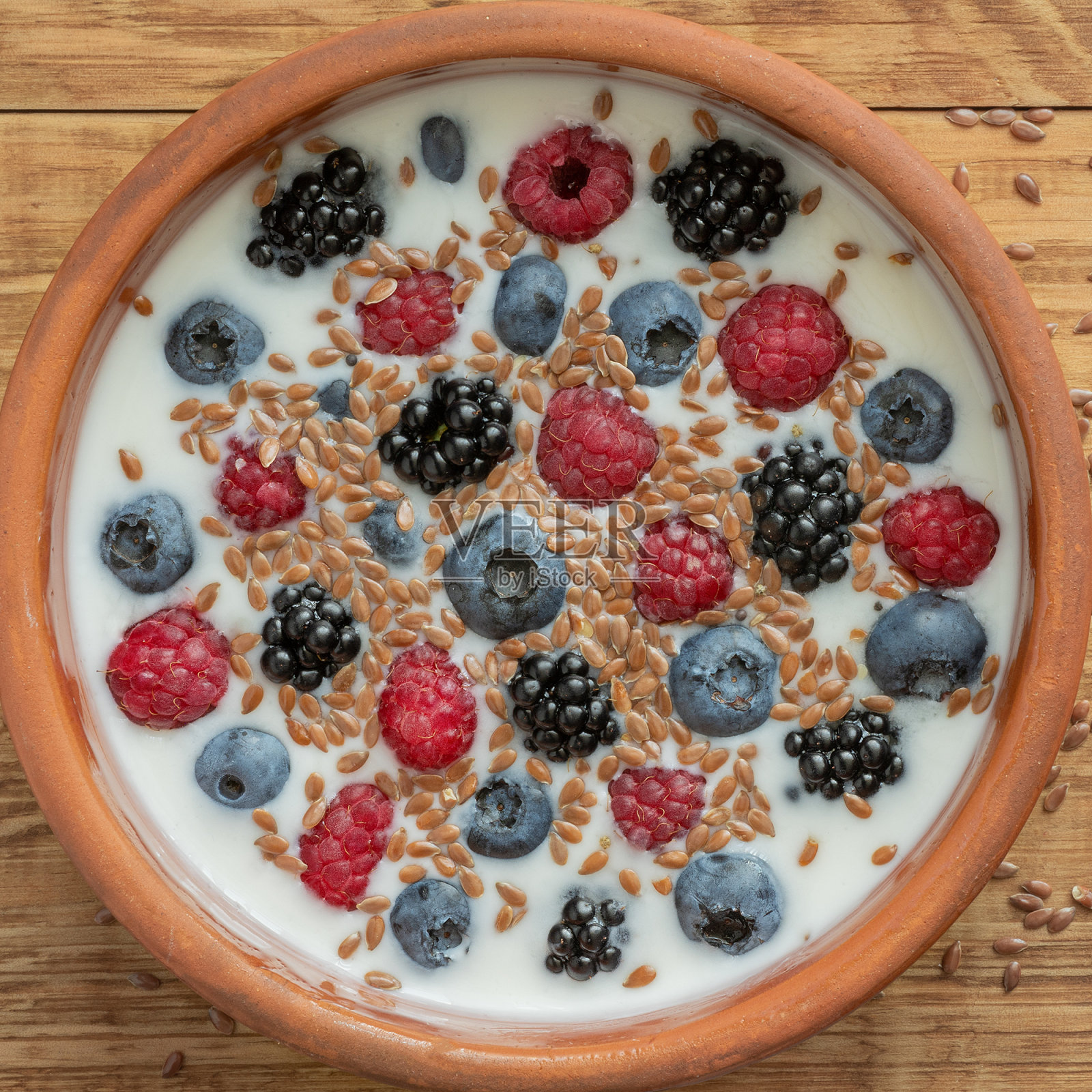 酸奶与蓝莓，树莓，黑莓，亚麻籽在粘土碗。素食菜。健康的早餐，健康的食物。餐厅、咖啡厅的菜单背景。照片摄影图片