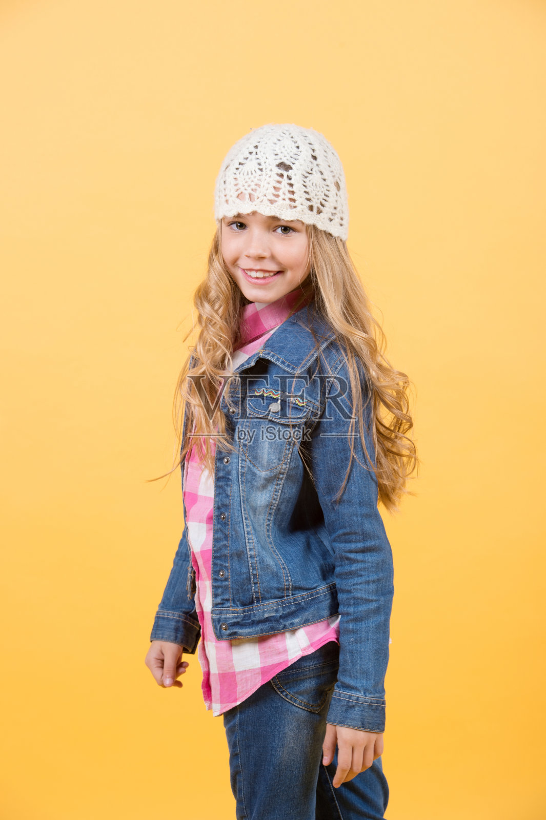 女孩穿着牛仔裤套装，帽子，橙色背景的格子衬衫照片摄影图片