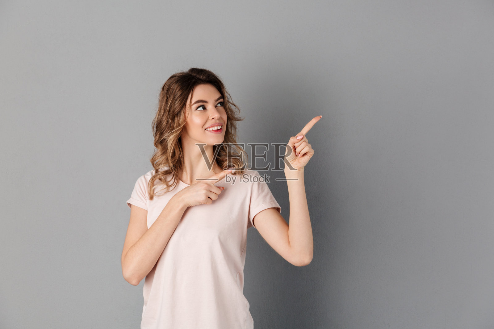 穿着t恤的快乐女人的形象指向别处照片摄影图片