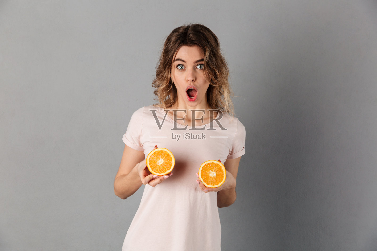 穿着t恤和橙子摆姿势的震惊女人照片摄影图片