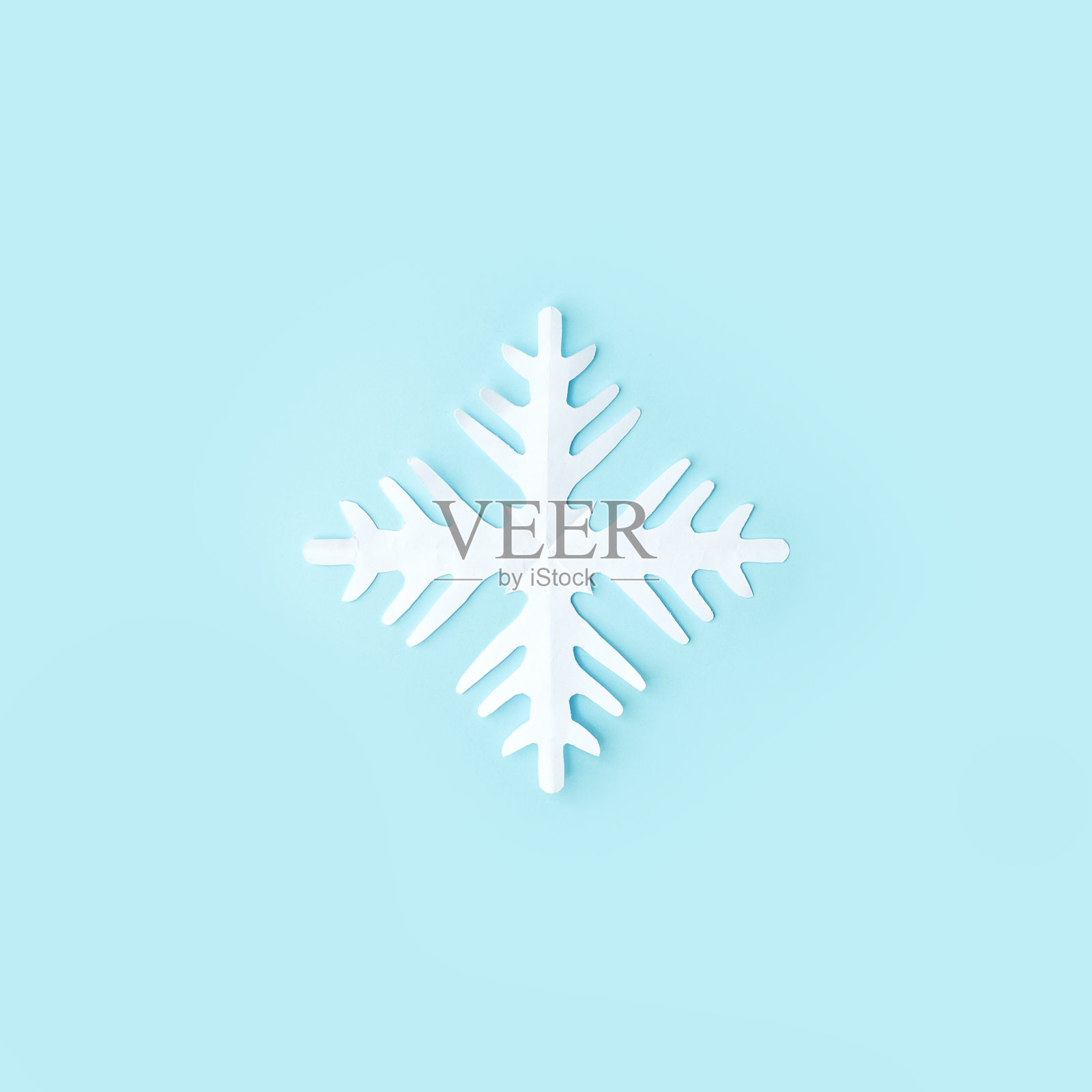 白色的雪花在蓝色的背景上从纸上剪下来。一个简单的传统圣诞工艺品diy项目。横幅为您的网站，传单，代金券，优惠券，冬季假期最小的概念照片摄影图片