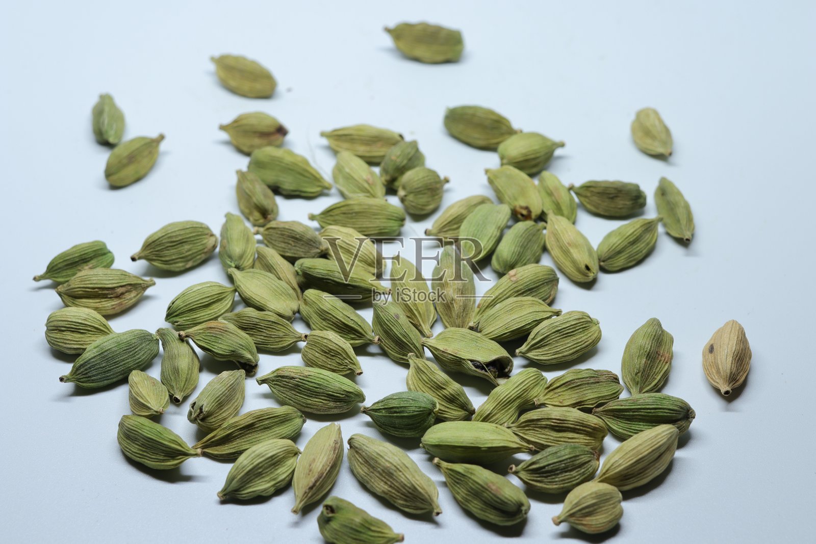 分离在白色背景上的绿色干小豆蔻种子照片摄影图片