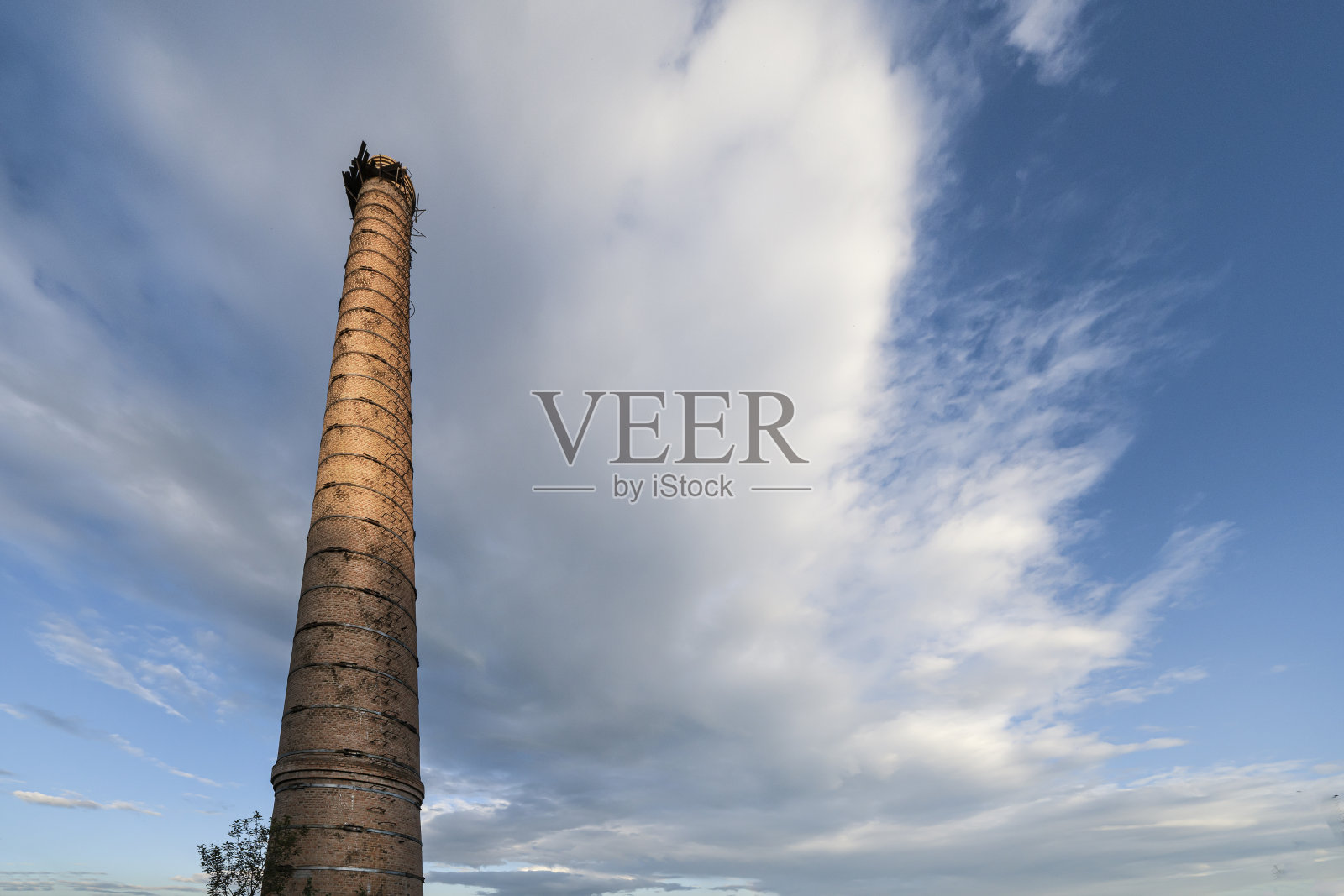 一座旧工厂的砖砌烟囱映衬着多云的蓝天照片摄影图片