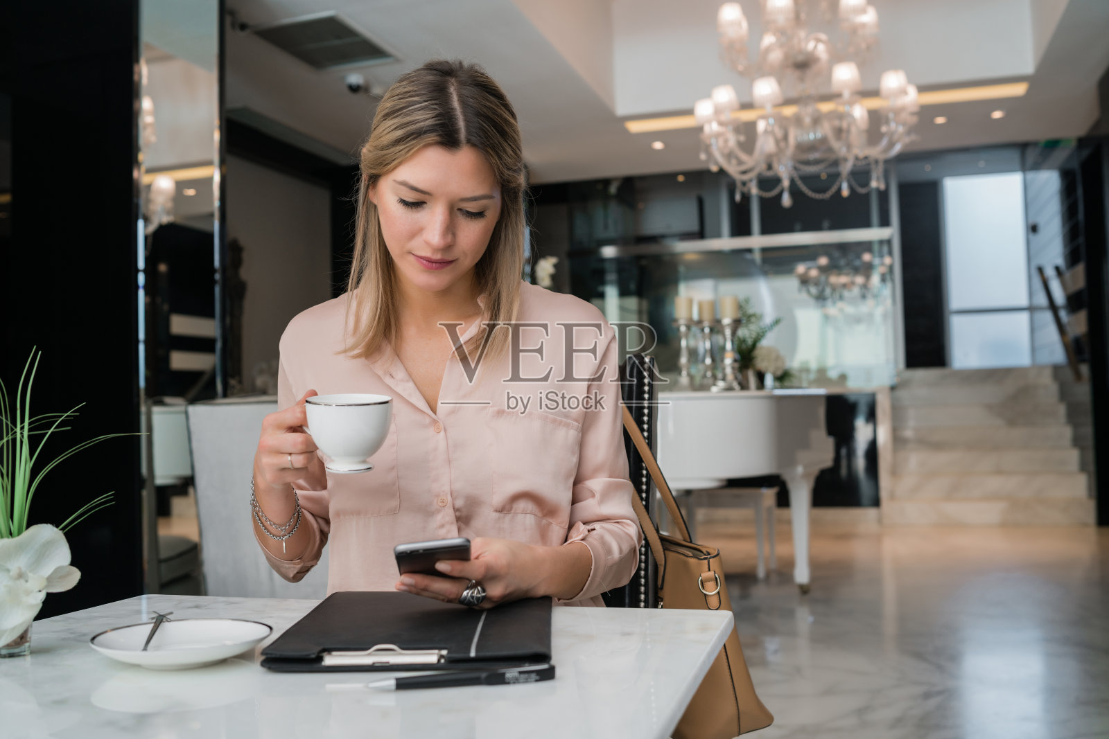 女商人在酒店大堂使用手机。照片摄影图片