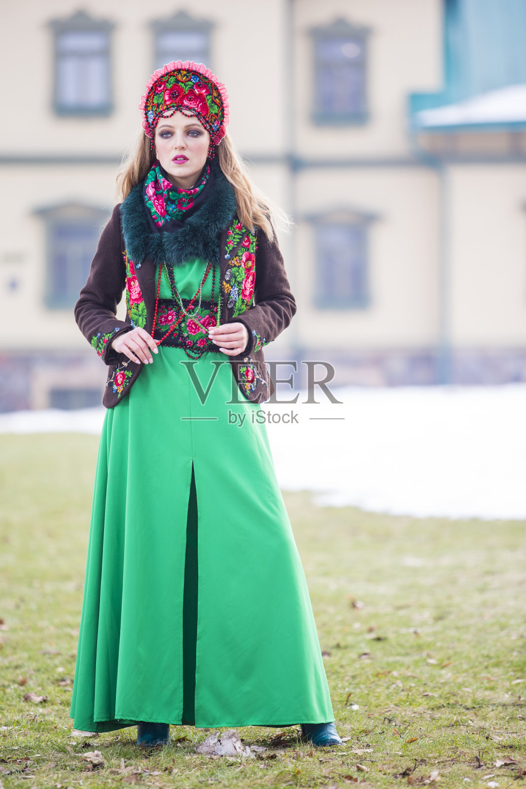 冬季独特的女性时尚概念。穿着时尚绿裙的金发美女和卡科史尼克。在冬天的户外摆姿势。垂直的图像照片摄影图片