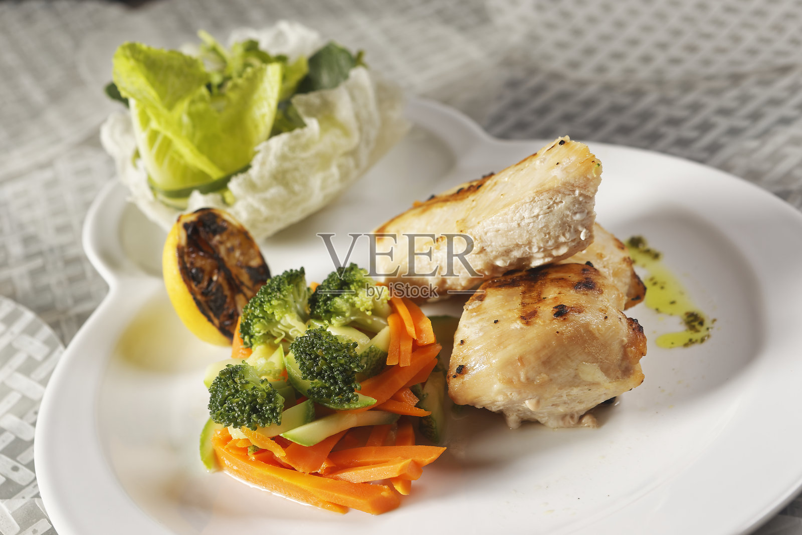 烤鸡胸肉配生菜沙拉，配西兰花，胡萝卜，南瓜和柠檬汁。照片摄影图片