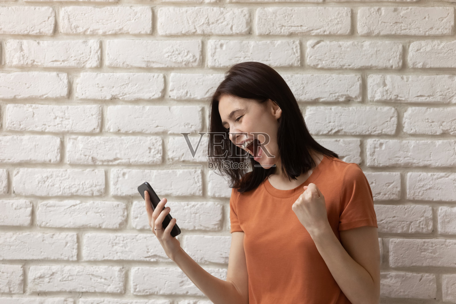 喜出望外的女孩在手机上赢得网上彩票照片摄影图片