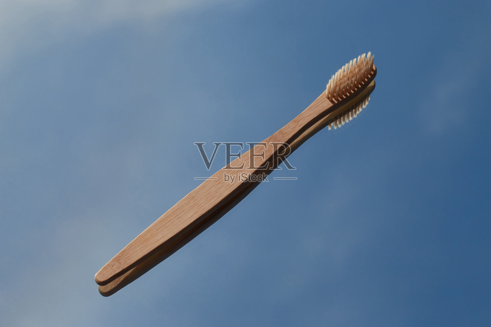 深蓝色的竹制牙刷倒映在镜子里，映衬着蓝天。口腔护理和保护照片摄影图片