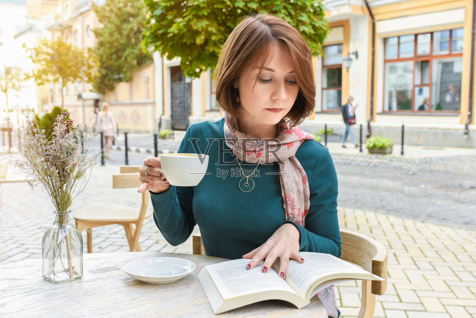 一个年轻的女孩在一家餐厅喝咖啡和看书。照片摄影图片