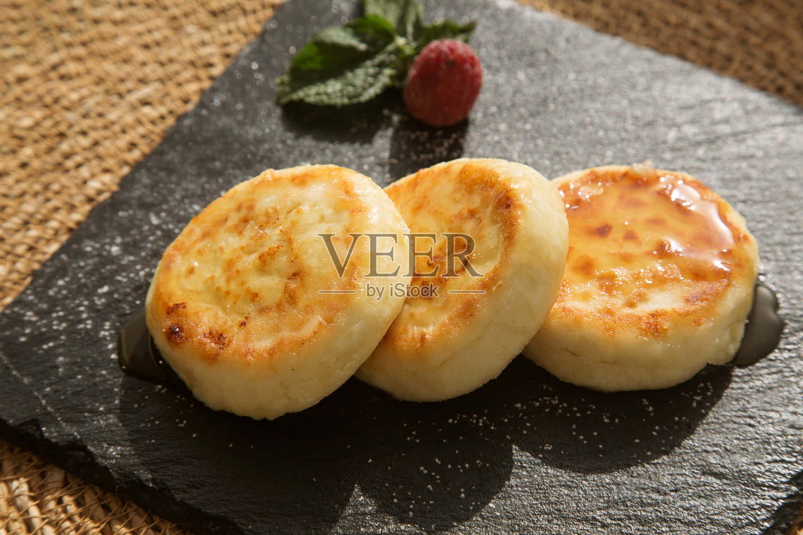 香草芝士蛋糕(白软干酪煎饼)淋上蜂蜜放在一个黑色的盘子里照片摄影图片