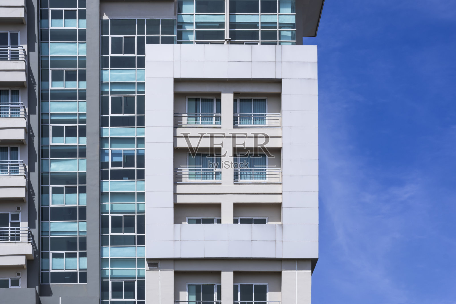 现代高层建筑外观以蓝天为背景的几何矩形玻璃窗和阳台照片摄影图片