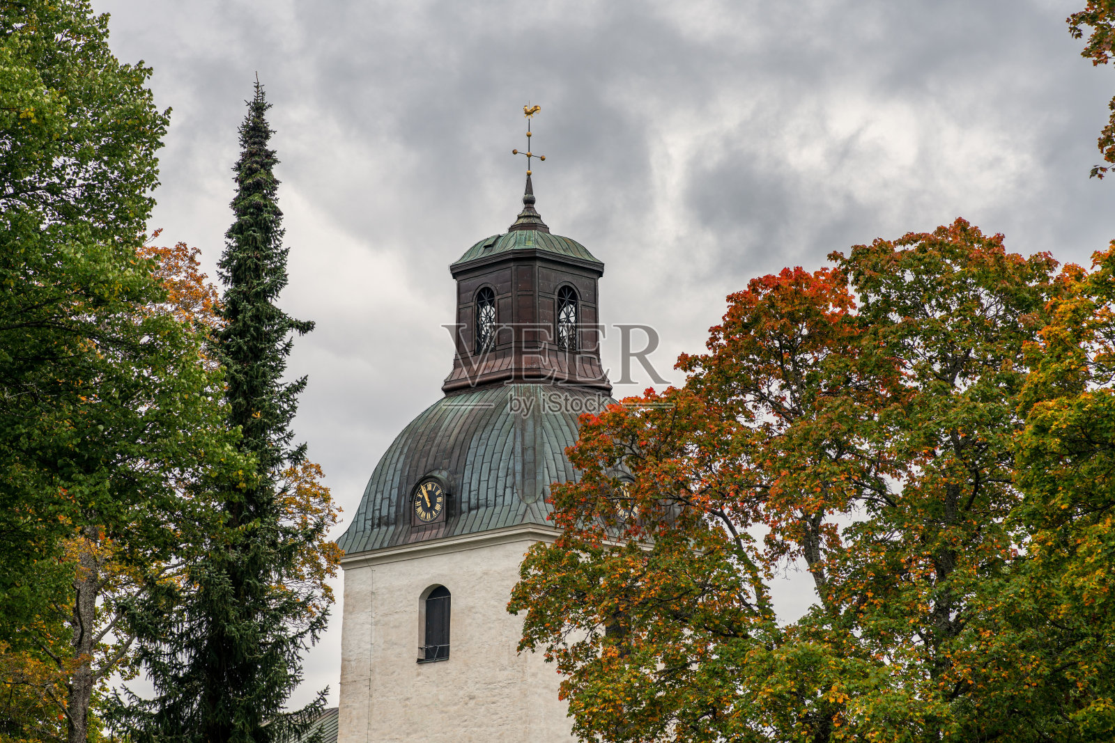 古老的教堂塔楼被秋色的树木环绕照片摄影图片