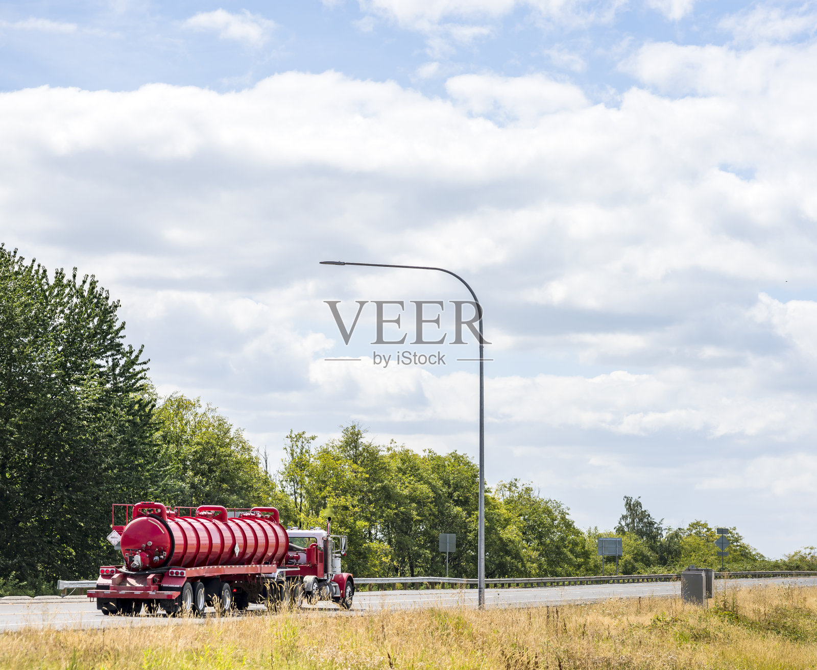 日驾驶室大钻机半挂车在罐式半挂车中运输货物，用于运输化学和易燃物质运行在夏季道路上照片摄影图片