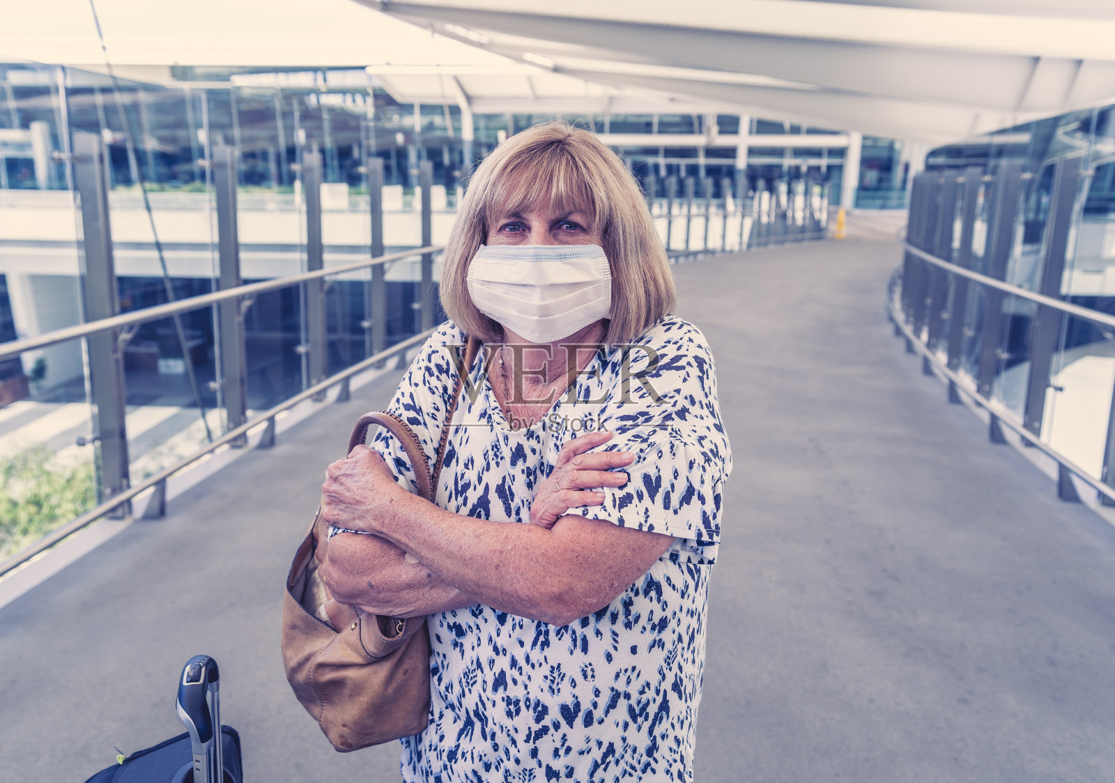 2019冠状病毒病和新诺尔玛旅游。因担心被隔离和感染新冠病毒回国，在机场候机楼戴防护口罩的老年妇女。照片摄影图片