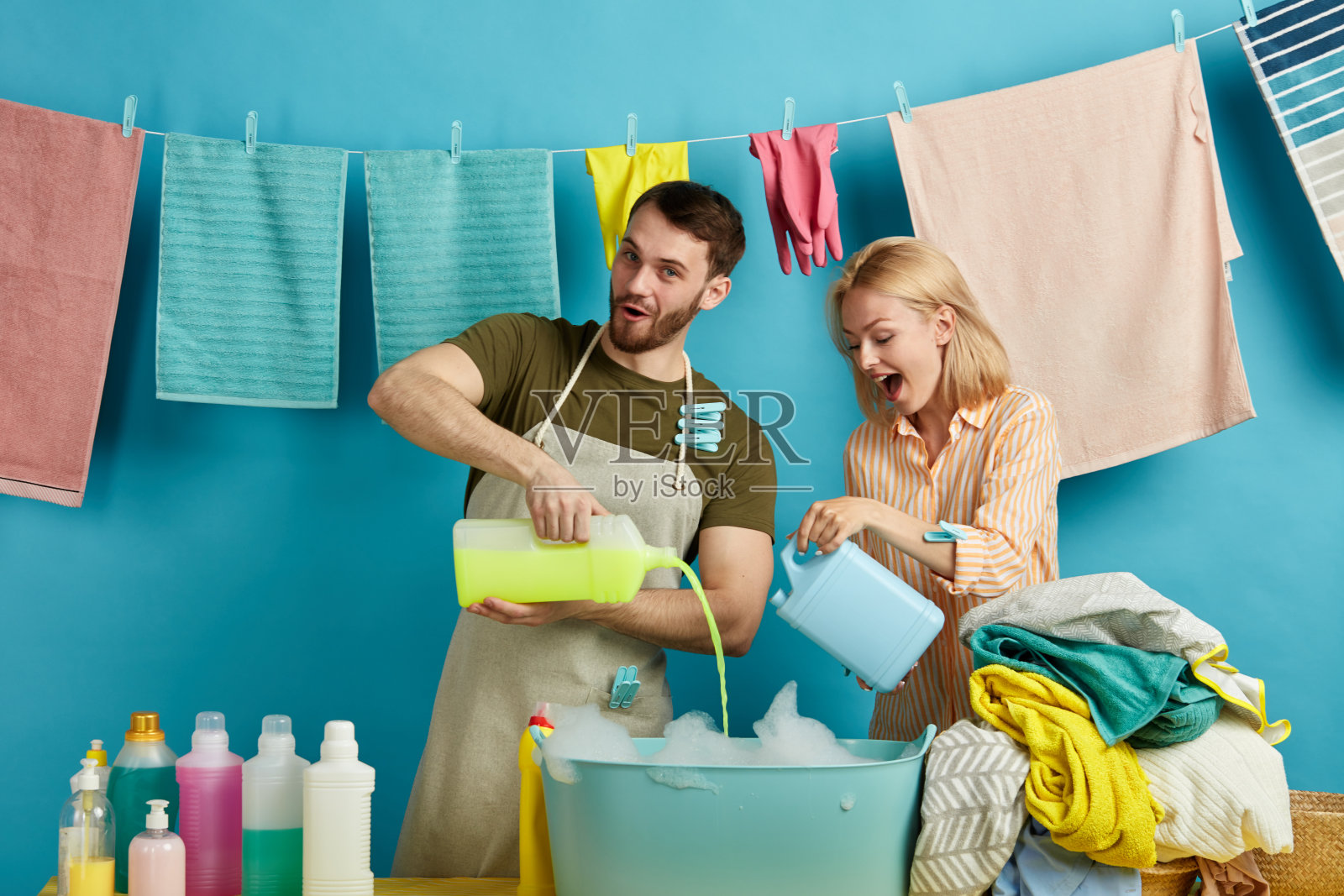 一对积极的年轻夫妇拿着几瓶肥皂对着镜头摆姿势照片摄影图片