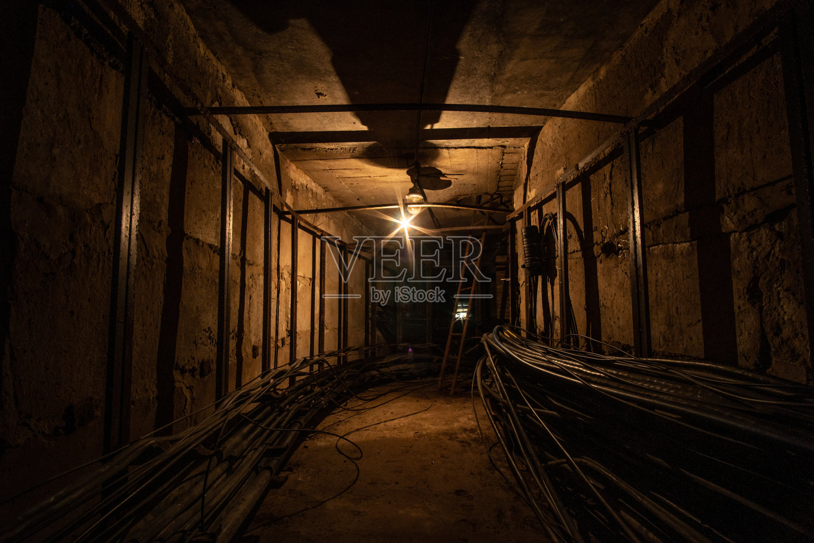 昏暗的混凝土电缆隧道由钨丝灯照明。照片摄影图片