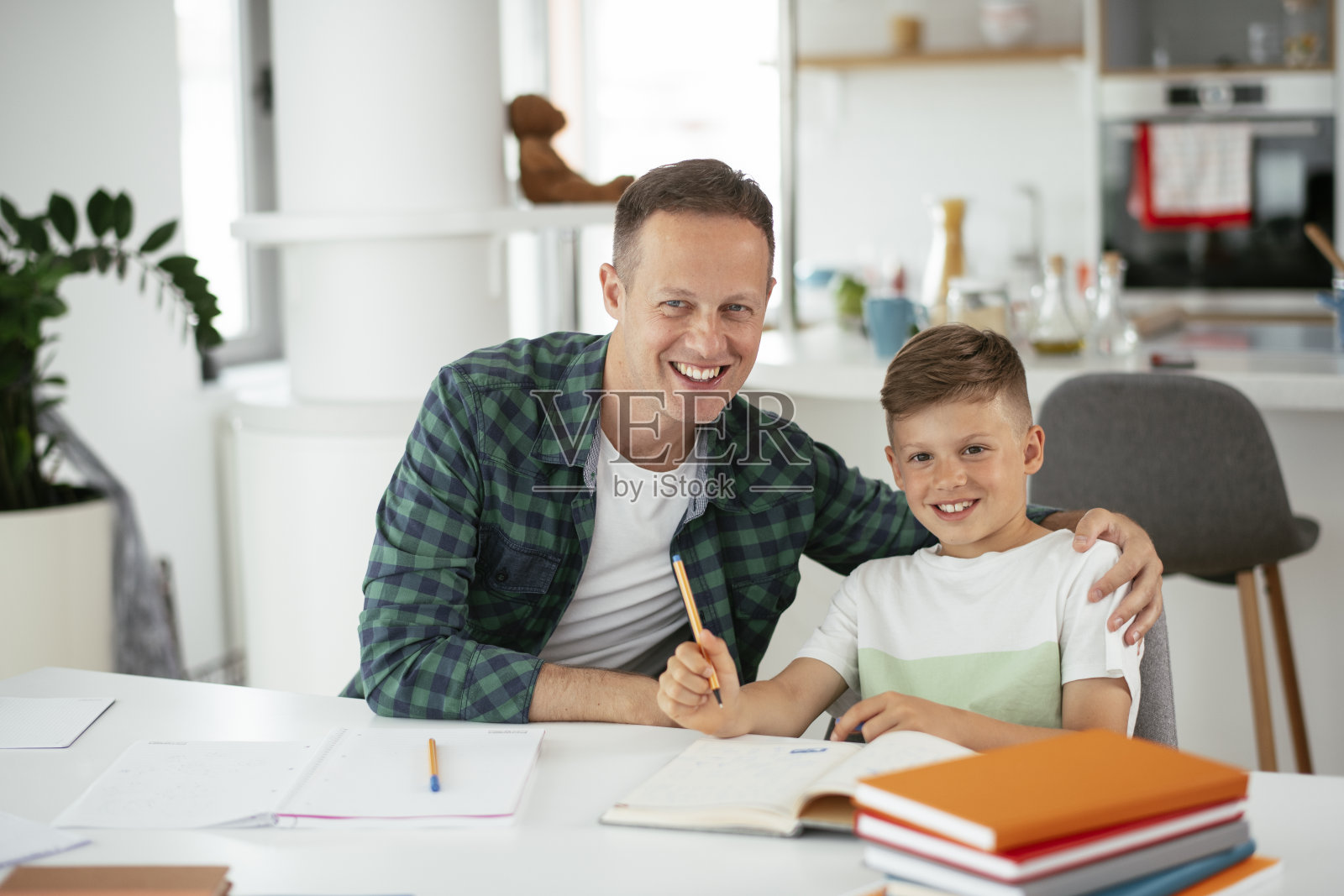 父亲在家里帮助儿子做作业。照片摄影图片