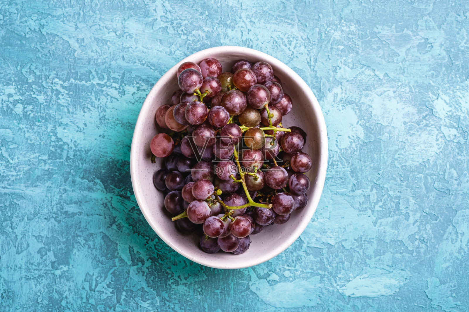 新鲜成熟的葡萄浆果在碗上蓝色纹理的背景，俯视图照片摄影图片