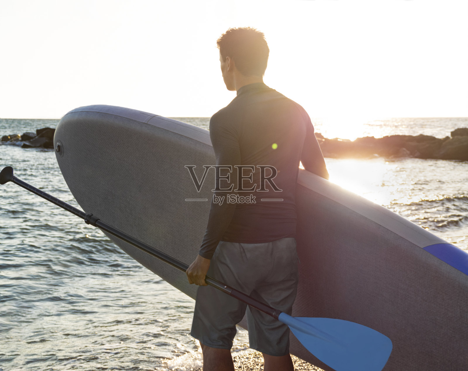 男人与SUP和桨在海滩上照片摄影图片