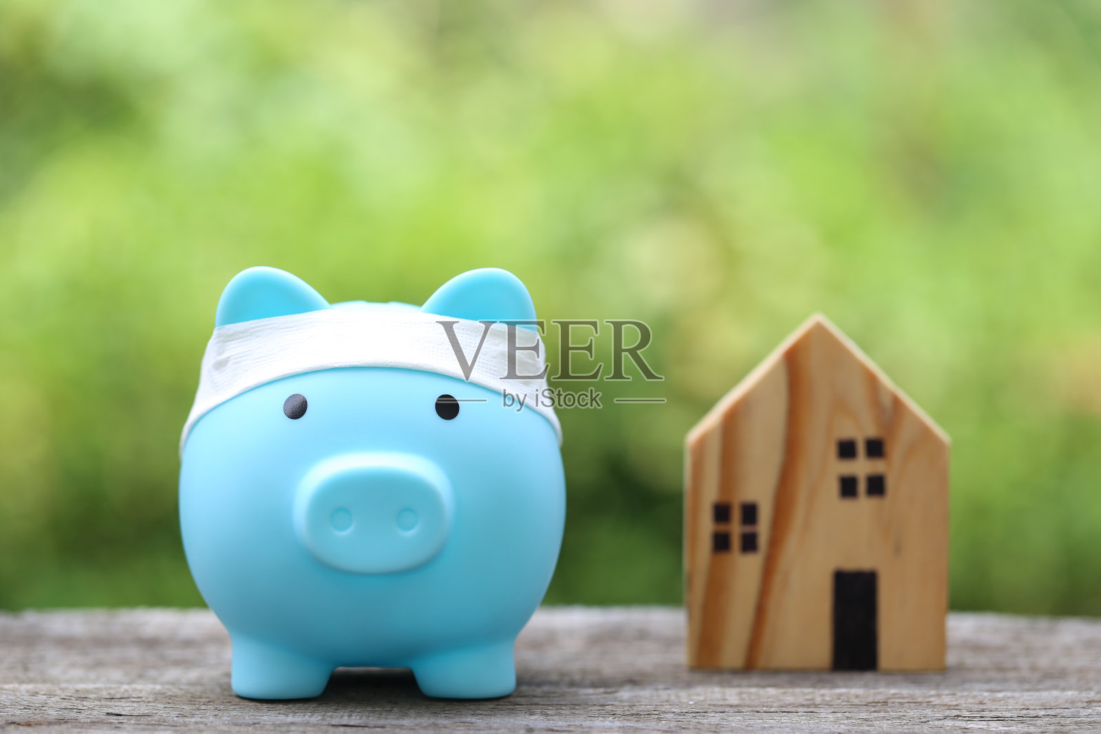 存钱罐以一堆硬币和模型房为背景，以自然绿色为背景，商业投资和房地产概念照片摄影图片